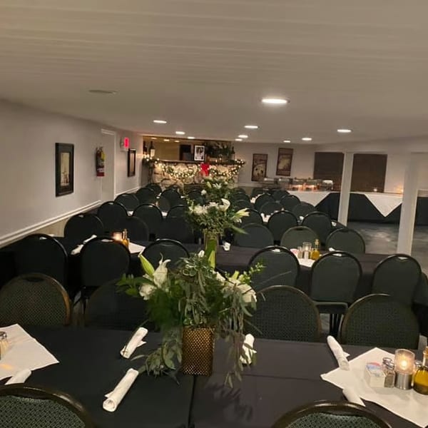 A large dining room set for an event with long tables, chairs, and floral centerpieces.