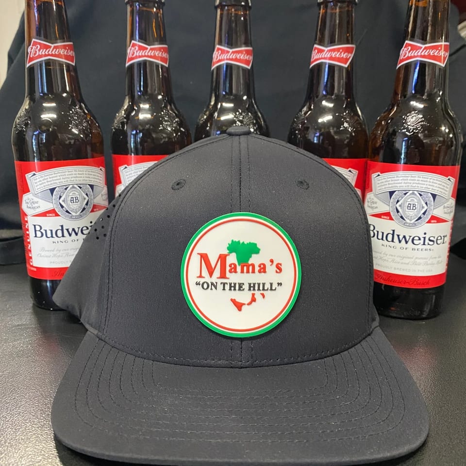 Black Mama's "ON THE HILL" baseball cap in front of five Budweiser beer bottles.
