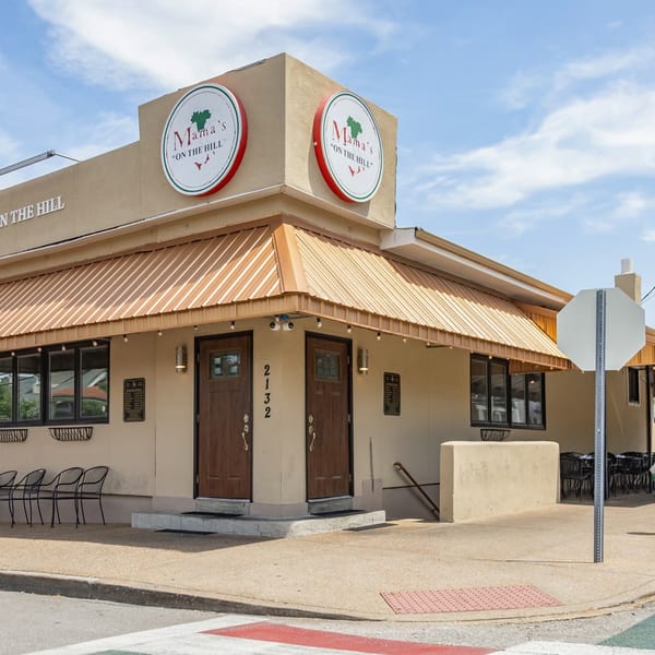 Mama's On The Hill restaurant exterior with brown awnings, outdoor seating, and a red, white, and green fire hydrant.